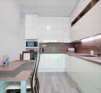 A kitchen in a 3-room apartment with a wooden decor floor and light furniture.