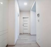A hallway in a 3-room apartment with a wooden decor floor and white doors.