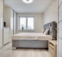 Stylish bedroom in a 3-room apartment with a large bed, wardrobe, and wooden floor decor.