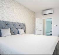 A bedroom with patterned wallpaper, a large bed, and air conditioning in a 3-room apartment.