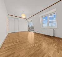 A room in a family house with a wooden decor floor, a wooden beam, and large windows.
