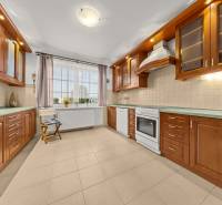 A kitchen in a family house with cabinets in colored wood and ceramic flooring.