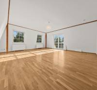 A bright room with wood-patterned flooring and large windows in a family house.