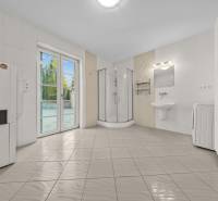 A bathroom in a family house with a shower, a washing machine, and large doors to the terrace.