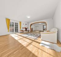 A bright living room with wood-patterned flooring, a fireplace, and yellow curtains in a family house.