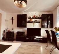 Living room of a three-room apartment with a wooden decor floor, dining table, and wall unit.