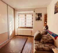 A room in a 3-room apartment with a wood-patterned floor, a sofa, and a built-in wardrobe.