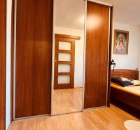 Bedroom in a 3-room apartment with wood-patterned flooring, a wardrobe, and a painting.