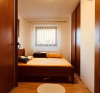 A bedroom in a 3-room apartment with a wooden decor floor and large wardrobes.