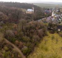 Gemerské Teplice capture recreational lands with a wooded landscape and a church in the background.