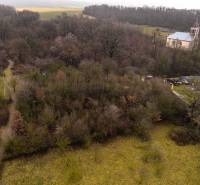 Recreational plots in Gemerské Teplice surrounded by forest and a church in the background.