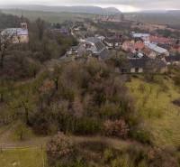 A view of greenery, houses, and a church in Gemerské Teplice on recreational grounds.