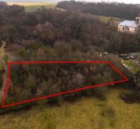 Recreational plots in Gemerské Teplice surrounded by trees with a historic church building in the background.