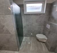 A bathroom in a family house with tiled walls and a shower enclosure.
