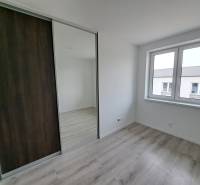 A room in a family house with a wooden decor floor and a large mirrored wardrobe.
