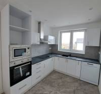 A kitchen in a family house with white cabinets and built-in appliances.
