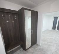 A hallway with a coat rack and a mirror in a family house with a wooden decor floor.
