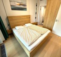Bedroom in a two-room apartment with a wooden decor floor and a picture above the bed.