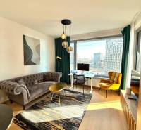 A bright living room with a sofa and wood-patterned flooring in a two-room apartment.