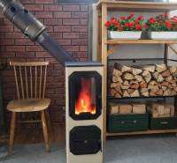 A solid fuel fireplace with a supply of wood and flowers on the garden shelf.