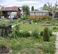Gardens on Brežný Row in Poprad with cottages, greenery, and a relaxation corner.