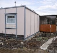 Gardens on Brežný Riadok in Poprad depict a wooden cottage with a surrounding garden.