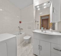 White bathroom with a bathtub and sink in a 4-room apartment.