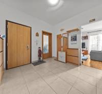 A hallway in a 4-room apartment with a living room, light-colored walls and decorations, and a floor with a wooden decor.