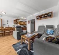 Living room and kitchen with a gray set, wooden furniture, and a floor with a wood decor.