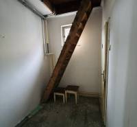 Narrow room with a wooden staircase and a window in a family house.