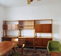 The interior of a family house with carpets, wooden furniture, and a dining table in a medium-sized room.