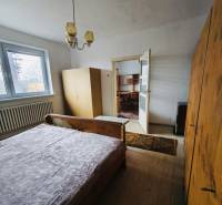A bedroom in a family house with wooden floor decor, simple furniture, and a chandelier.