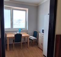 Interior of a family house with a window, table, chairs, and a wooden-patterned floor.