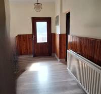 A hallway in a family house with a wooden decor floor and wooden wall paneling.