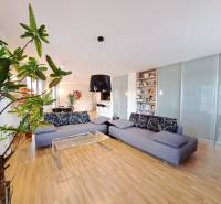 Living room in a two-room apartment with a wooden-patterned floor and a comfortable sofa.