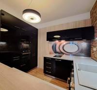 A kitchen in a 2-room apartment with a wood-patterned floor and dark cabinets.