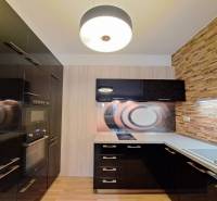 A kitchen in a 2-room apartment with a wooden decor floor and stone cladding.