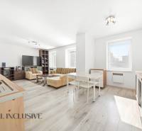 A spacious living room with wood-patterned flooring in a three-room apartment.