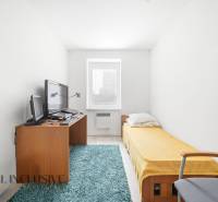 A room with a single bed, carpet, and a desk with a computer in a 3-room apartment.