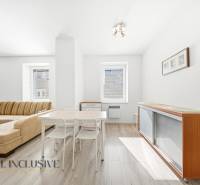 A bright living room in a 3-room apartment with wood-patterned flooring and comfortable seating.