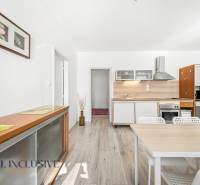 A kitchen in a 3-room apartment with light furniture and a wooden decor floor.