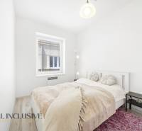 Bright bedroom with a bed, lamp, and window, 3-room apartment with wood-patterned flooring.