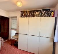 A room in a family house with a sofa, a cabinet, and a carpet, a window with a view.