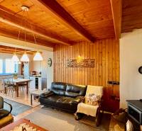 Living room with a fireplace, leather sofa, and kitchen in a family house with wooden decor.