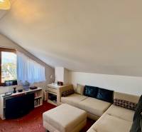 Interior of a family house with a sofa under a sloped ceiling and a window with a view.