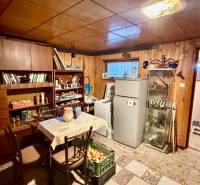 The interior of a family house with wooden panels, a refrigerator, and full shelves.