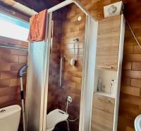 A bathroom in a family house with brown tile cladding, a shower corner, and a window.