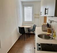 A kitchen in a 2-room apartment with a sink, stove, and a table with chairs.