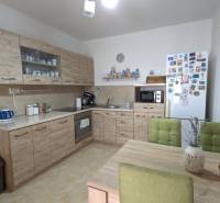 A kitchen in a family house with wooden decor furniture, green chairs, and decorations.