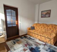 Living room with an orange sofa and a television, wooden decor flooring, family house.
